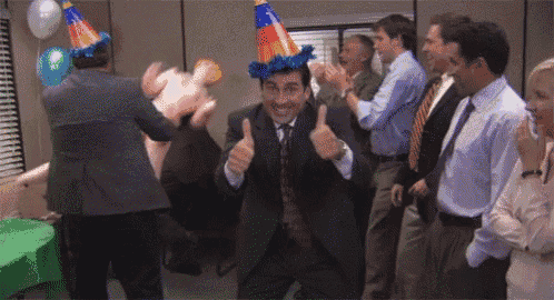 a man in a suit and tie is giving a thumbs up at a party while a group of people applaud .
