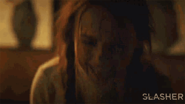 a woman is screaming with blood coming out of her mouth in a slasher movie .