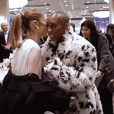 two women are kissing in a crowded room .