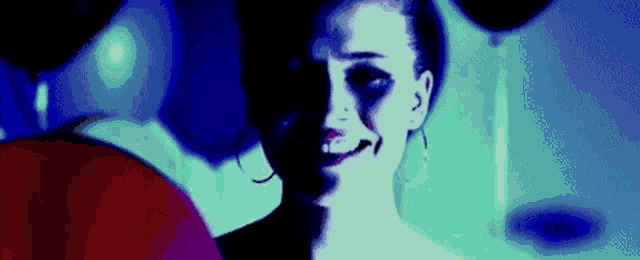 a woman in a dark room with balloons in the background is smiling .