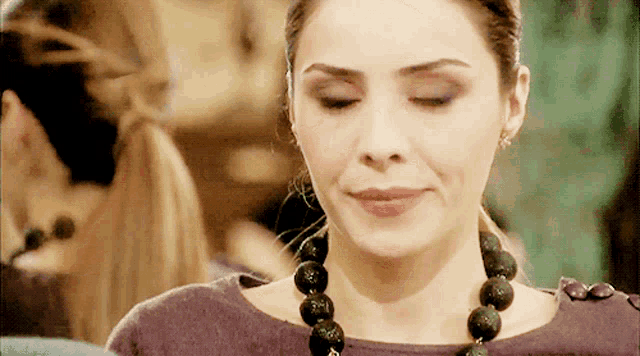 a woman wearing a purple top and a black necklace