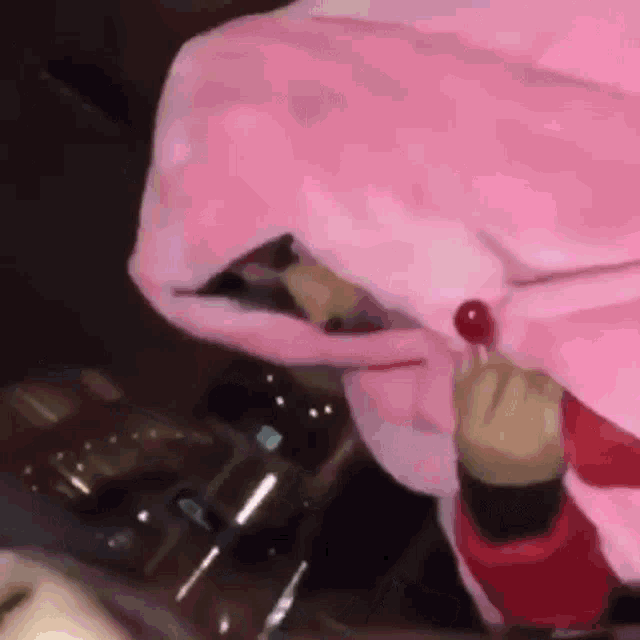 a person wearing a pink hoodie is holding a lollipop in their mouth .