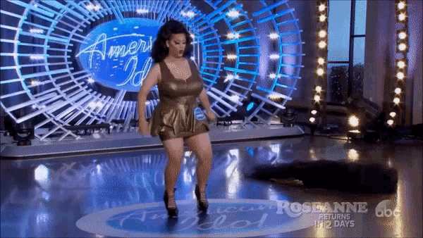 a woman is dancing on a stage in front of a sign that says america 's idol