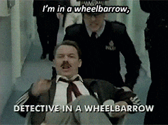 a man in a wheelbarrow is being escorted by two police officers