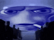 a group of people are standing in front of a large blue face with a cigarette in his mouth .