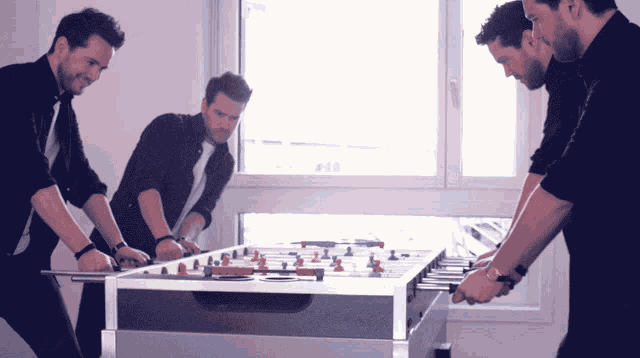 a group of men are playing foosball in front of a window