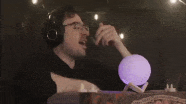 a man with glasses is playing with a purple moon lamp
