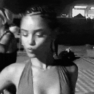 a black and white photo of a woman in a halter top making a face .