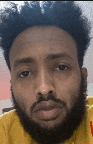a close up of a man 's face with a beard and a yellow shirt