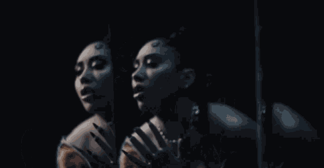 a woman with a ponytail and a necklace looks at herself in a mirror