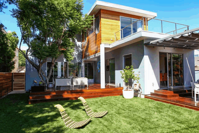 the backyard of a modern house with lawn chairs