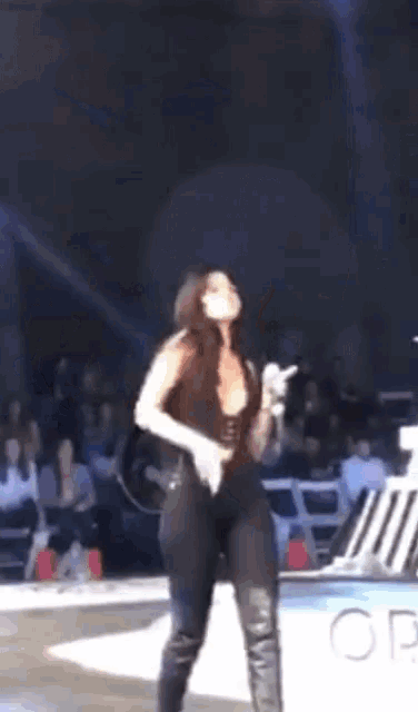 a woman in a black bodysuit is dancing on a stage in front of a crowd