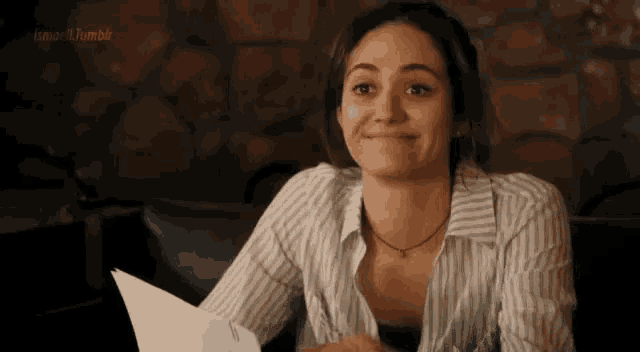 a woman in a striped shirt is sitting at a table with a piece of paper in her hand .