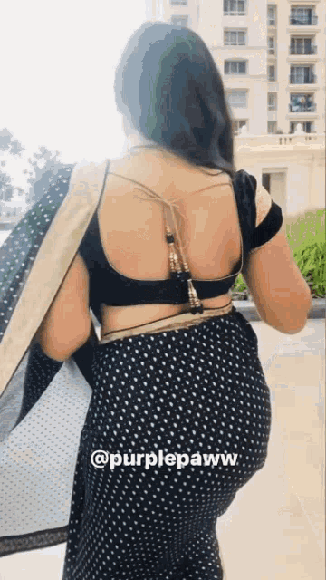 the back of a woman wearing a black and gold polka dot saree .