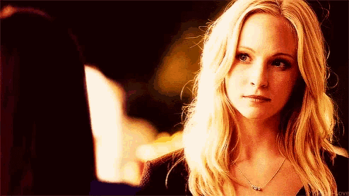 a woman with blonde hair and a necklace is looking at the camera with a serious look on her face .