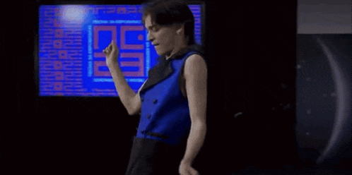 a man in a blue tank top is standing in front of a computer screen that says jm