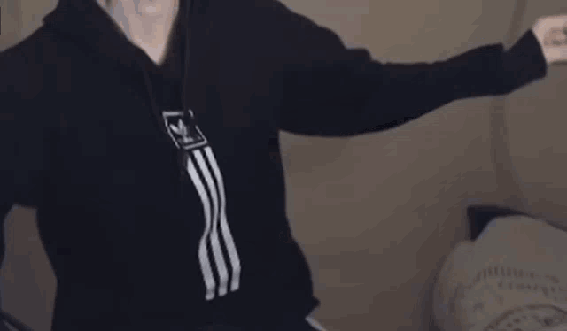 a man wearing a black turtleneck and blue shorts is dancing with his arms in the air