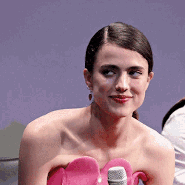 a woman in a pink dress is smiling and holding a microphone