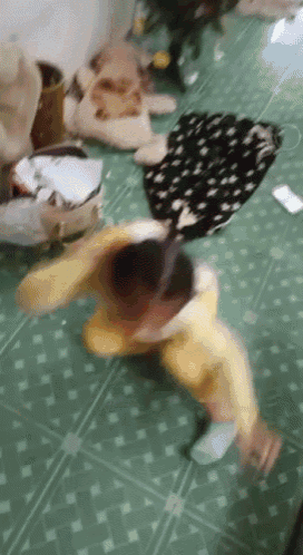 a child in a yellow outfit is laying on the floor