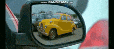 a yellow car is reflected in the rear view mirror of a car ..
