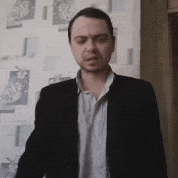 a man in a suit stands in front of a wall that has flowers on it
