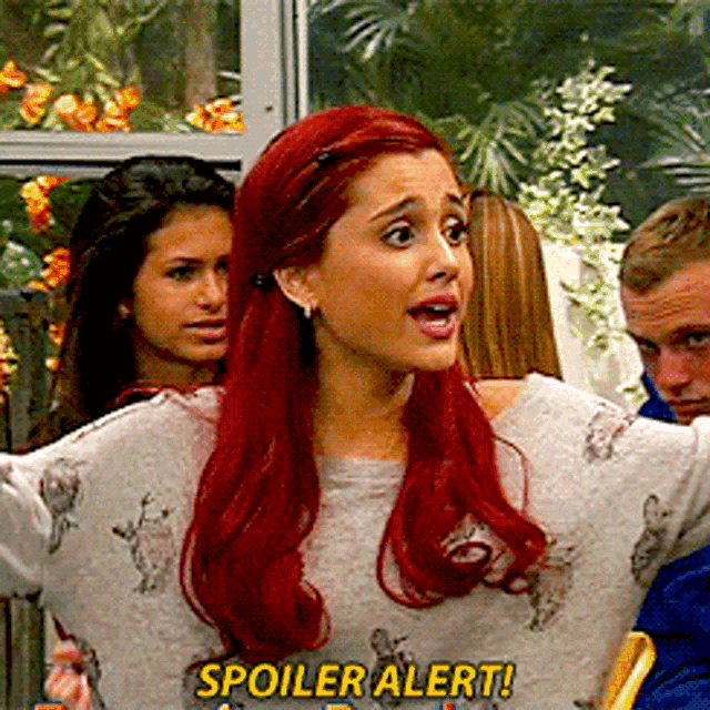 a woman with red hair is wearing a grey sweater that says spoiler alert