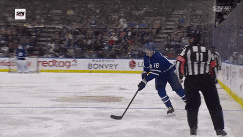a hockey player with the number 18 on his jersey stands on the ice