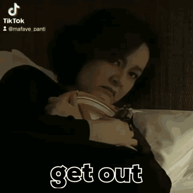 a woman is laying on a bed with the words get out written in white letters