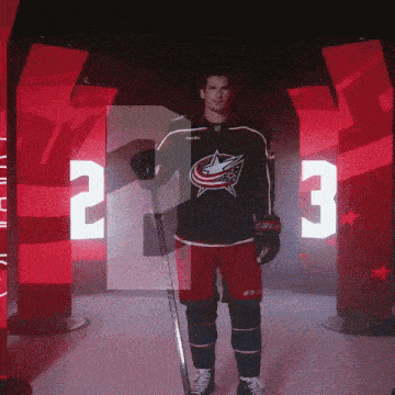 a hockey player in a bauer jersey stands in a hallway with the number 3 behind him