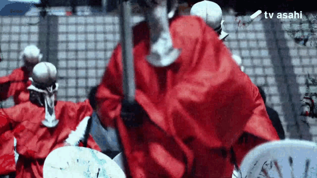 a group of people wearing red robes and white hats are standing in front of a brick wall .