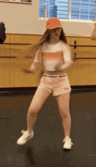 a young girl is dancing in a dance studio wearing a hat and shorts .
