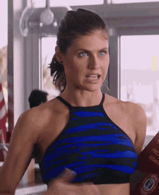 a woman in a blue and black striped halter top is standing in a restaurant .