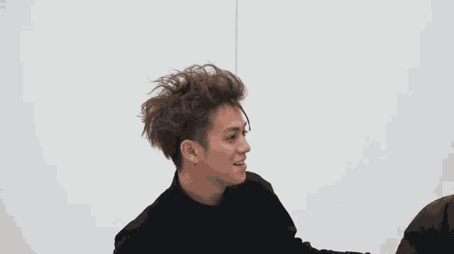 a young man with a messy haircut is wearing a black shirt