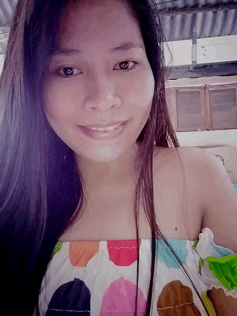 a woman wearing a polka dot off the shoulder top smiles for the camera