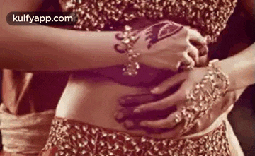 a woman with a tattoo on her arm is holding her stomach with her hands .