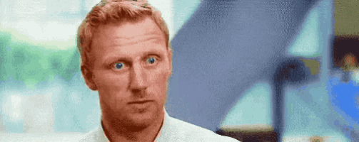 a man with red hair and blue eyes is looking at the camera with a serious look on his face .