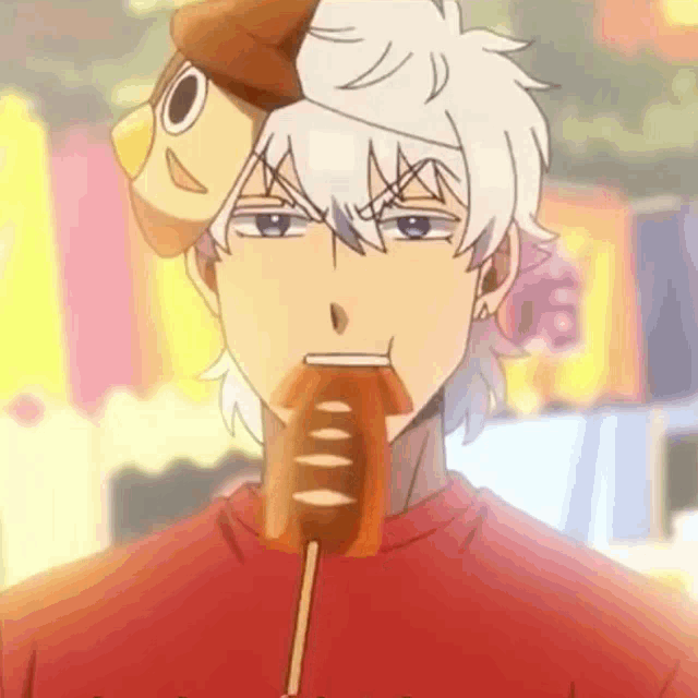 a man with a stuffed animal on his head is eating a hot dog .