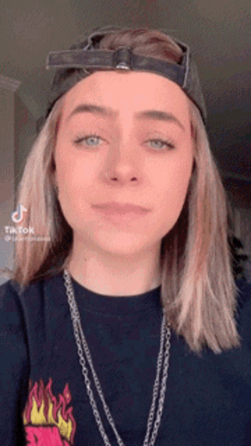 a woman wearing a hat and a necklace is a tiktok star