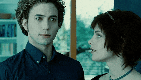 a man and a woman are looking at each other in a dark room
