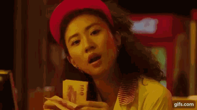 a woman in a red hat is holding a bunch of money in her hand .