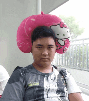 a young man wearing a soccer shirt has a hello kitty pillow on his head