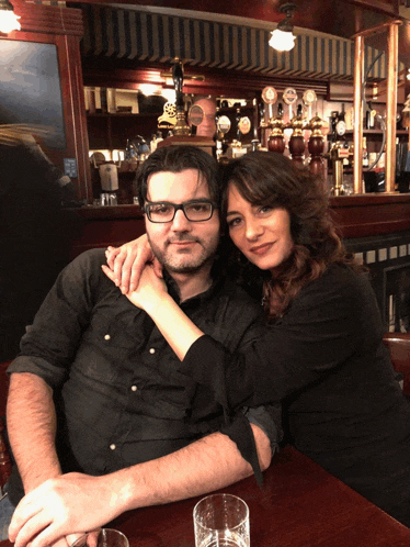 a man and woman are posing for a picture in a bar