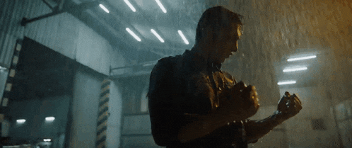 a man with a backpack is standing in the rain in a dark room .