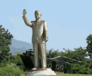 a statue of a man in a suit and tie waving