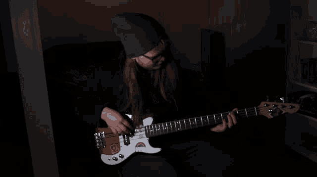 a girl in a blue beanie is playing a bass guitar