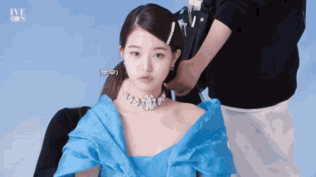 a woman wearing a blue dress and a necklace has the word ive on her face