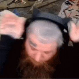 a man with a beard is wearing headphones and waving his hands .