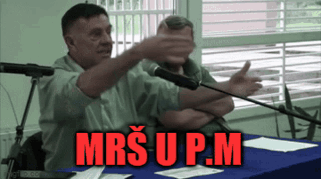a man speaking into a microphone with the words mrs u p.m. written in red