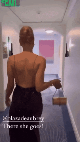 a woman in a black dress is walking down a hallway with the words " there she goes " above her
