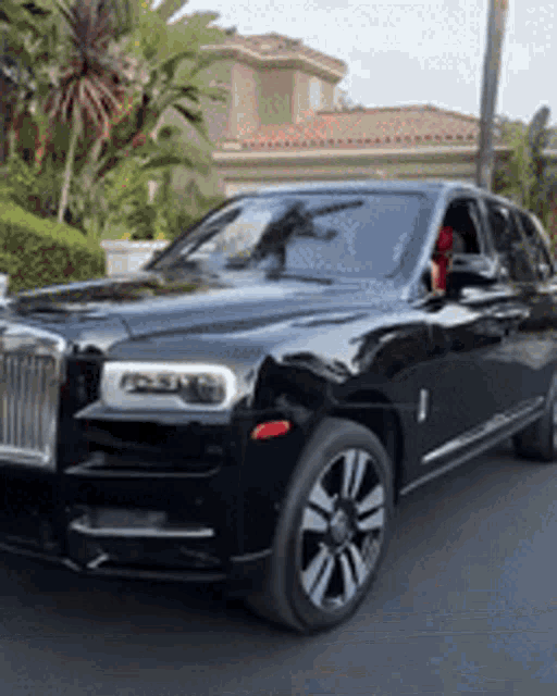 a black rolls royce parked in front of a house